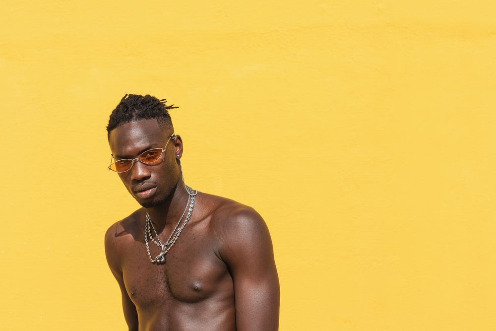 Serious Black man in trendy sunglasses near wall