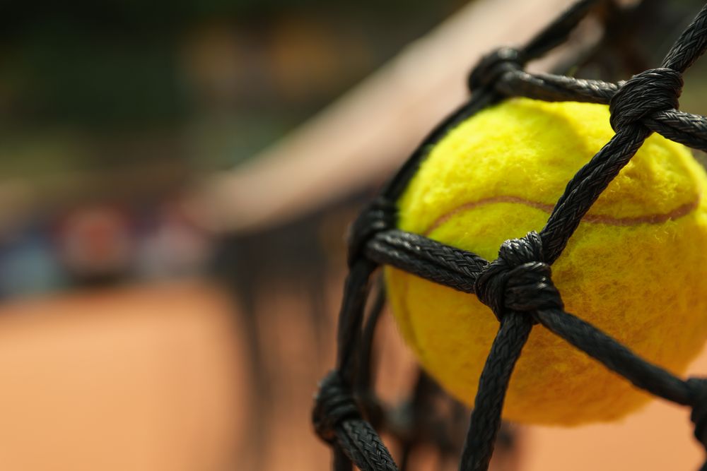 Tennis ball in net, close up and space for text