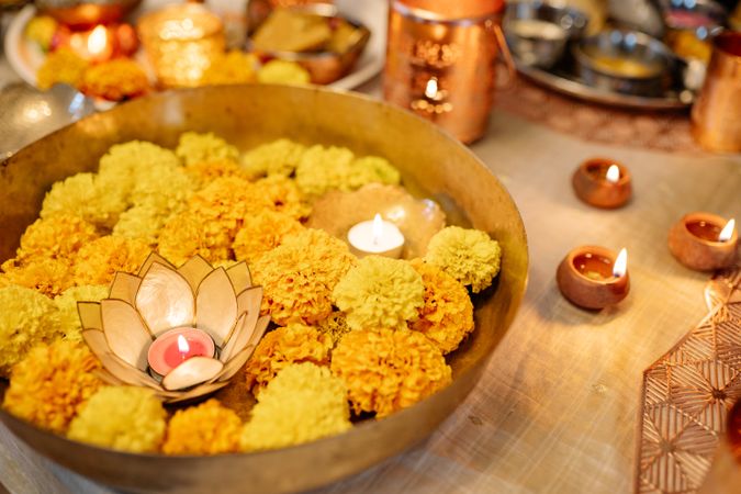 Bowl of marigold flowers with candle and diyas