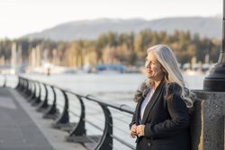 Confident smiling woman buttoning blazer outdoors near river