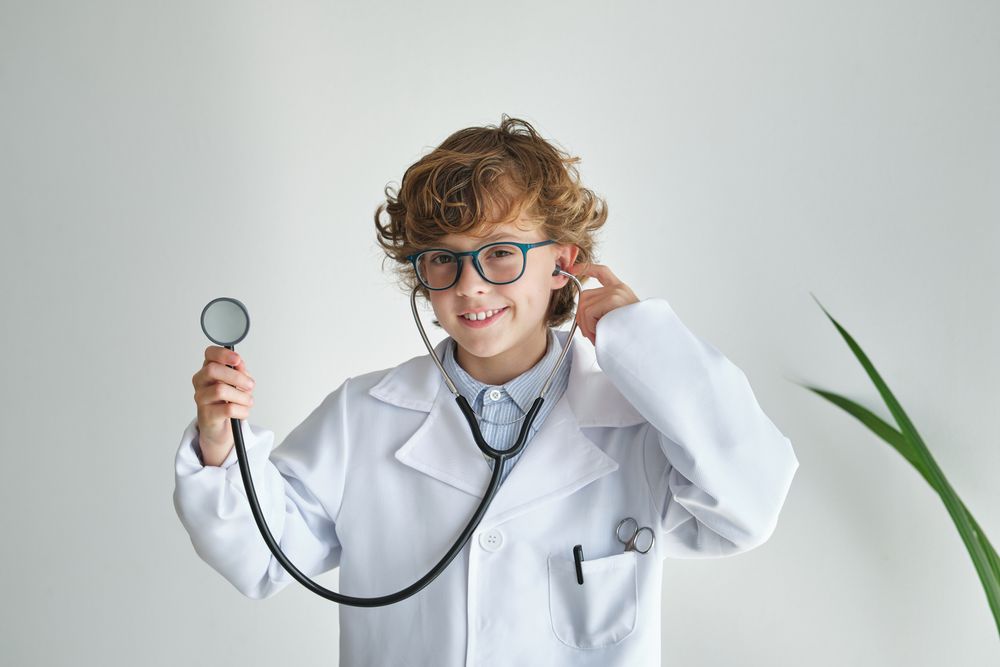 Smiling boy in medical uniform with stethoscope on white backgro