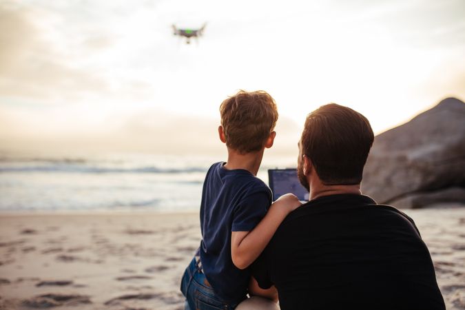 Father and son flying a drone over beach