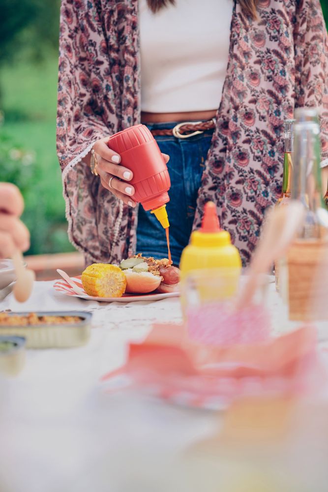 Woman pouring ketchup over an American hot dog