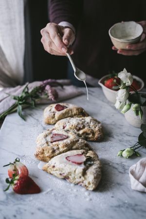 Crop person spilling sauce on scones