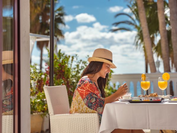 Cheerful woman having breakfast on terrace