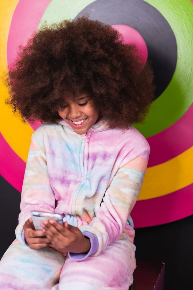 Smiling Black girl using mobile phone in studio