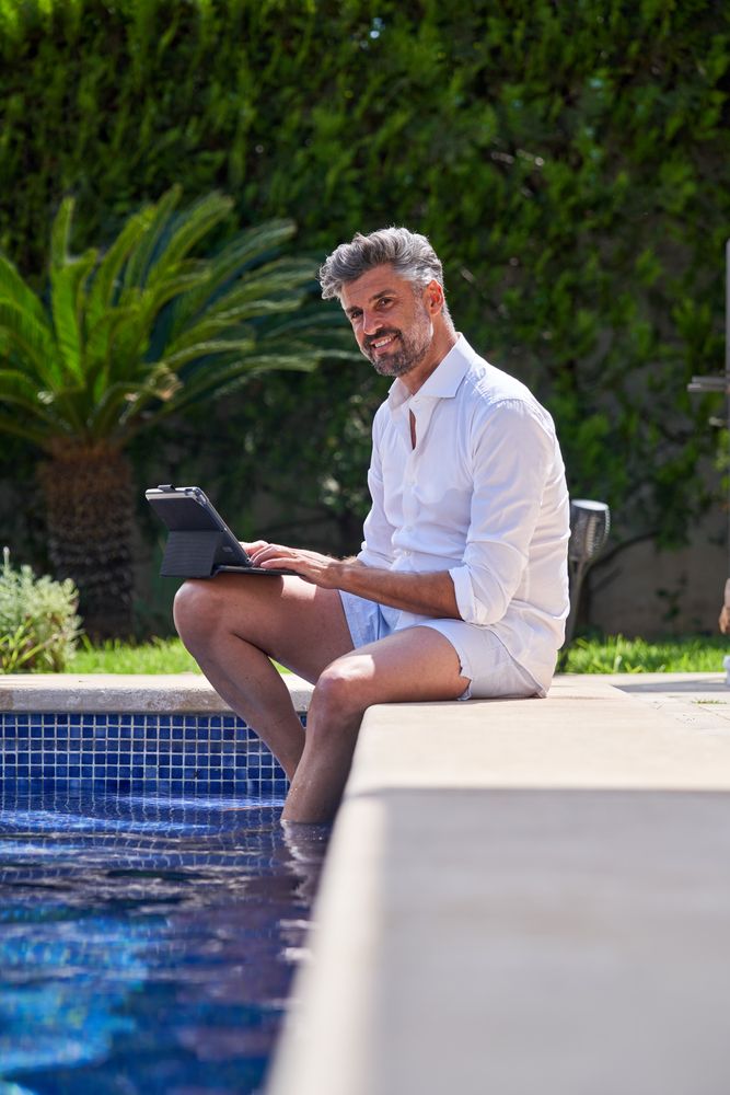 Adult man using tablet at poolside in summer