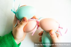 Hands holding pastel egg & pink egg decorations 56GgzN