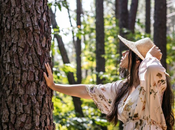 Young woman touching a tree in the forest