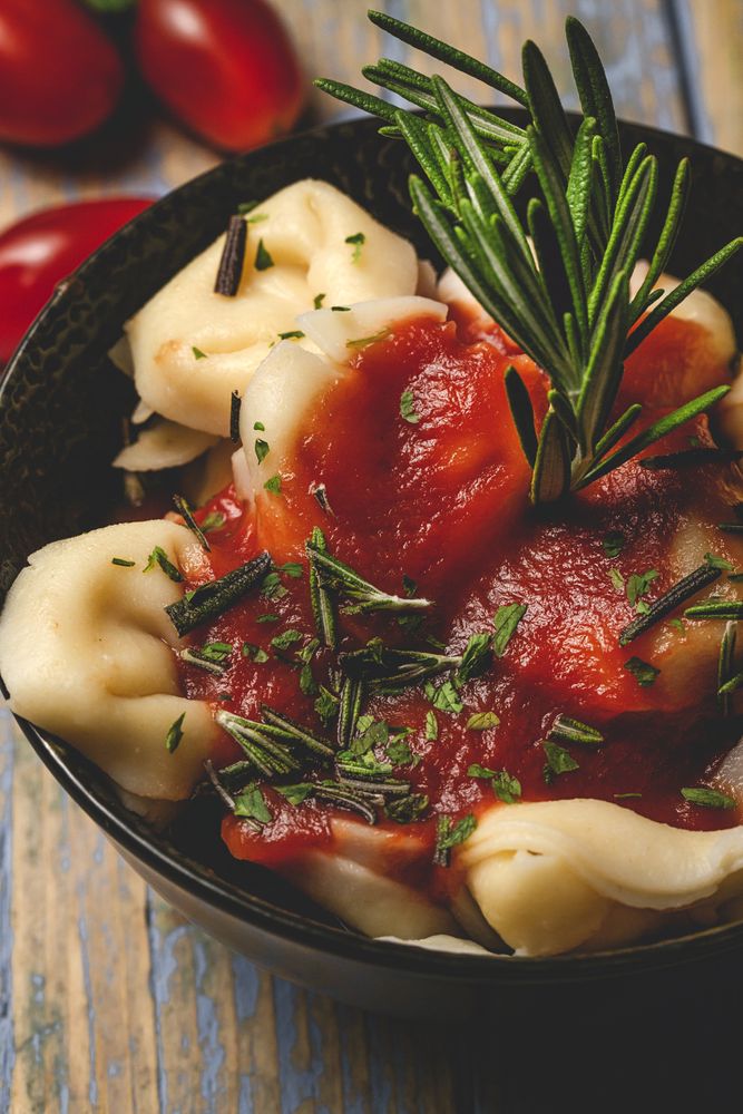 Plate of delicious ravioli with tomato sauce served on table