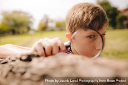Boy looking through magnifying glass on a sunny day 0Wz3pb