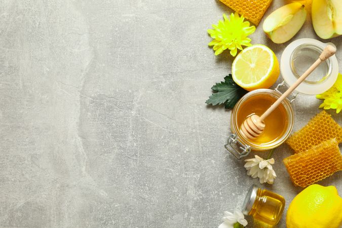 Flat lay with honey, flowers and fruits on grey background, copy space