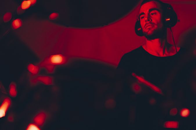 Man with drumsticks playing on drums in redness