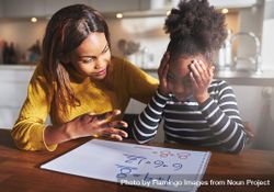 Black mother and daughter work through a frustrating math problem at home 5Qojmb