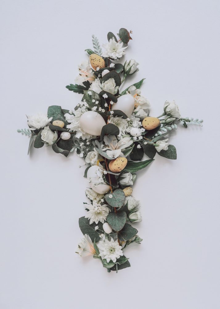 Easter layout with flowers and leaves in cross shape on light paper background