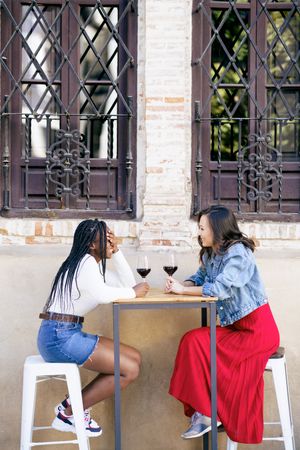 Female friends enjoying wine at an outdoor table at a restaurant, vertical
