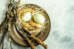 Top view of Easter holiday concept with pastel decorative eggs in nest on plate with pussy willow