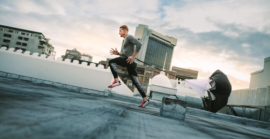 Man doing workout using resistance parachute on rooftop