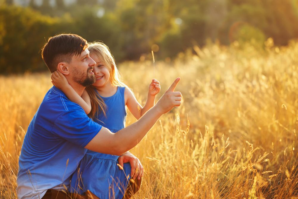 Dad and daughter playing together in field of long grass