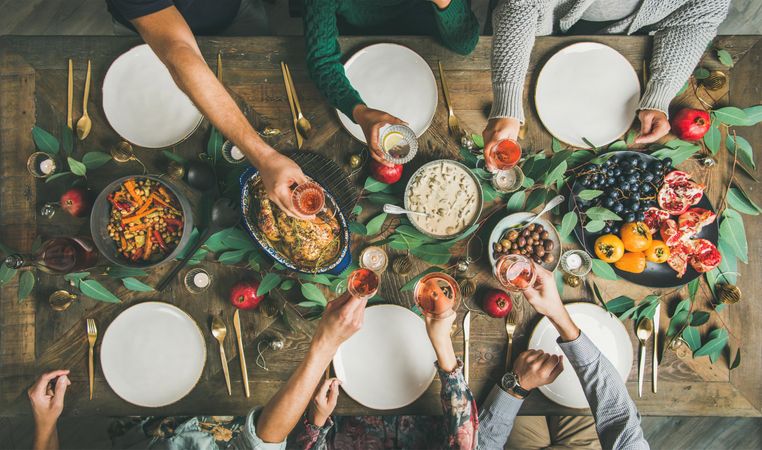 Group toasting wine at festive table with roasted chicken and pomegranates