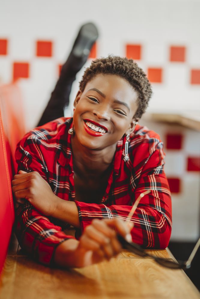 Gorgeous stylish Black woman lying on seats in cafe