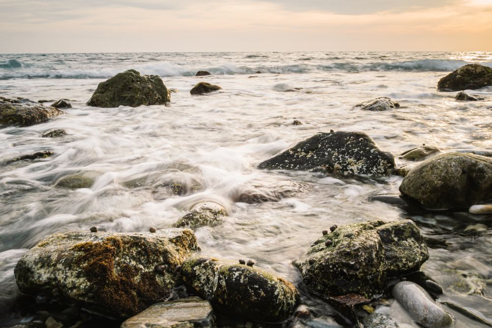 Stony seashore and waves at beautiful sunset