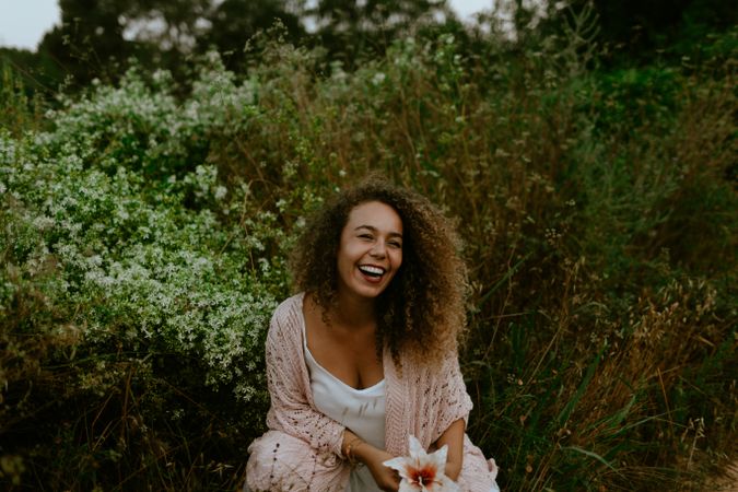 Smiling woman touching flower in forest