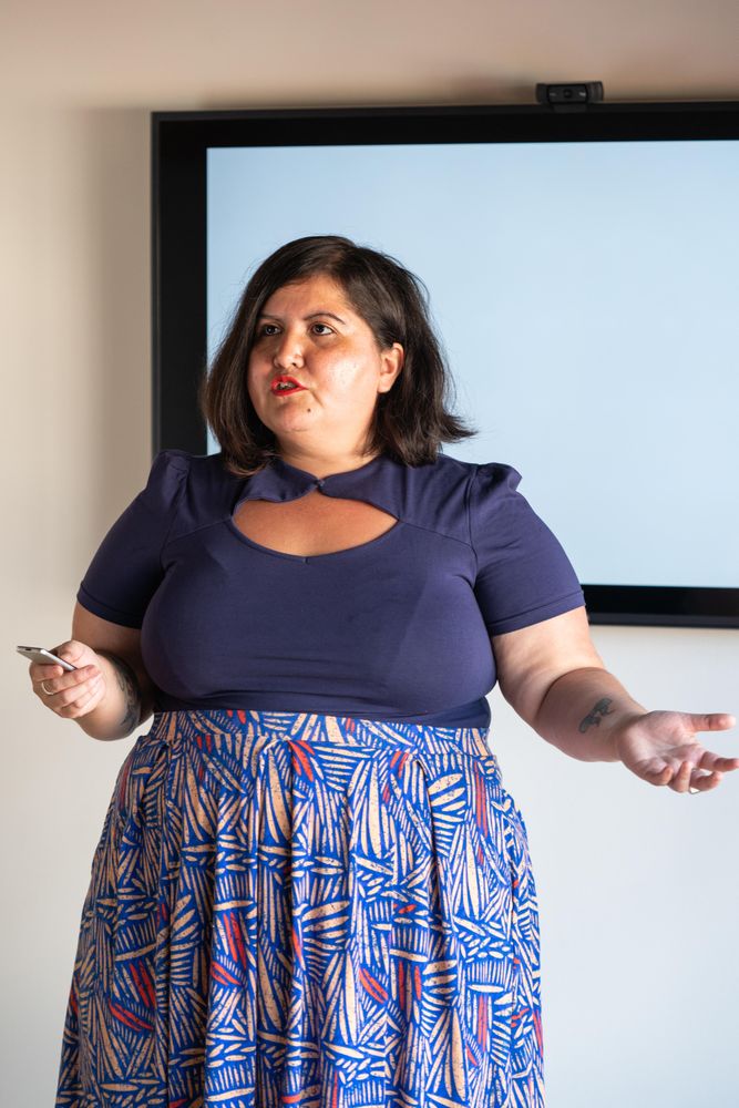Woman speaking intently with a screen behind her