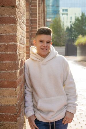 Portrait of smiling young male leaning against brick wall in the sunshine