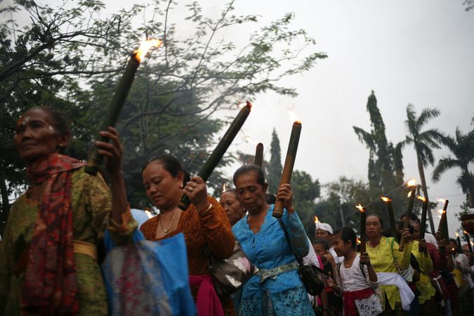 Group of mature Indonesian Hindu women with torches with lit flames marches during Nyepi day