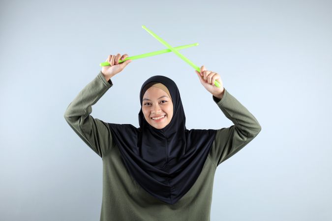 Asian Hijabi Female Holding Green Rip Stick for Pound Fit, Sporty Concept.