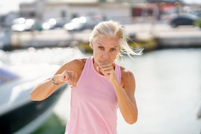 Mature woman practicing punches in a coastal pier
