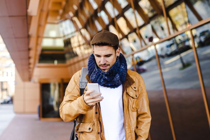 Stylish guy using smartphone outside modern building
