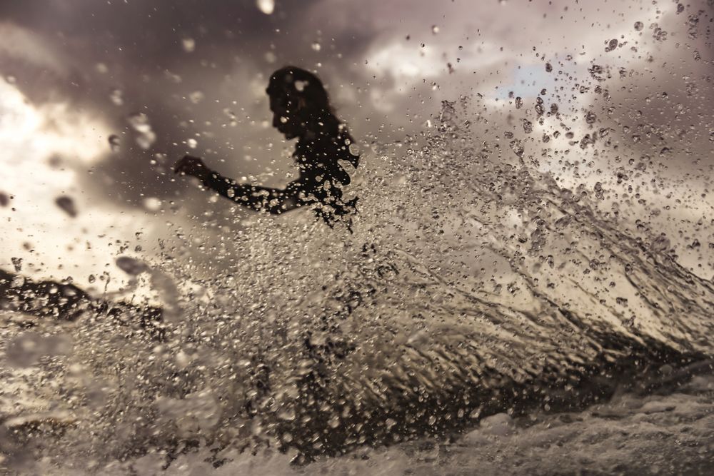 Woman on surf board floating on water between splashes