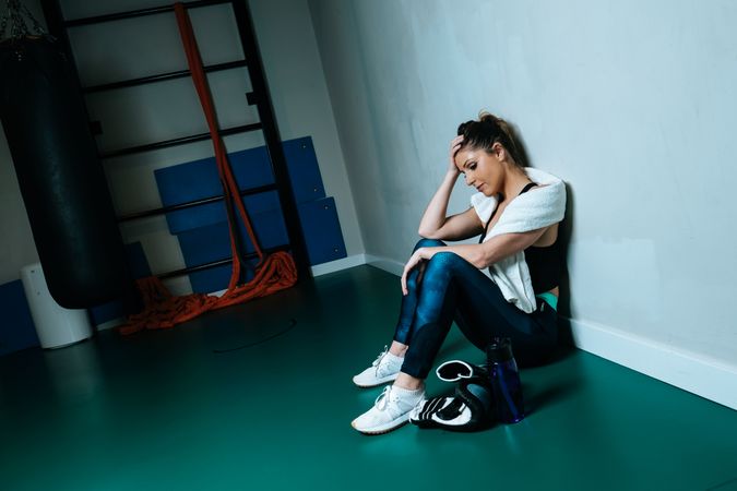 Sportswoman in boxing gloves sitting in gym