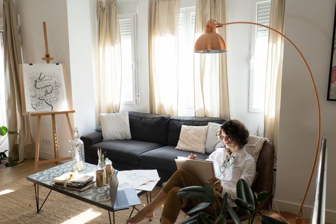 Woman writing on paper on sofa in room