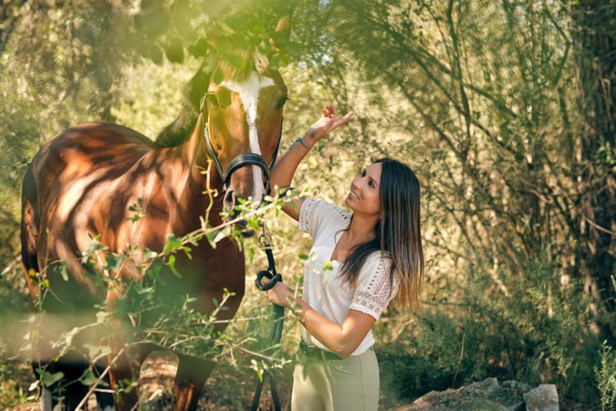 Smiling woman with horse in woodland