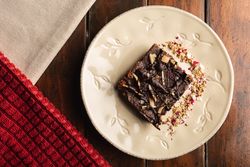 Tasty brown cake decorated with flakes on plate