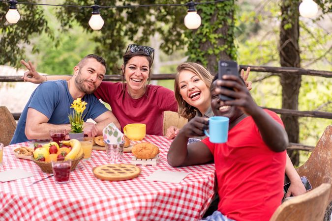 Diverse friends relaxing taking selfie at picnic table