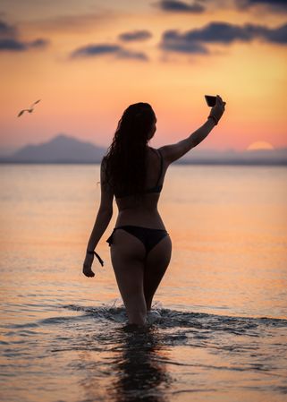 Seductive female taking selfie in water
