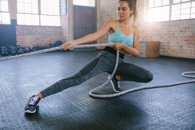 Shot of young woman exercising with rope at a gym