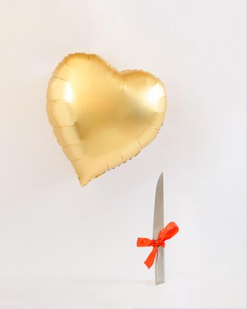 Heart balloon gold flying above a knife