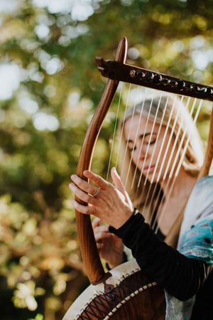 Sensual female musician playing lyre in garden