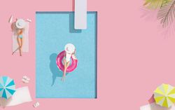 Barbie-like doll in donut ring in pool, with friend at poolside with parasols and towels