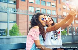 Young women wearing stylish sunglasses taking selfie together 0ya370