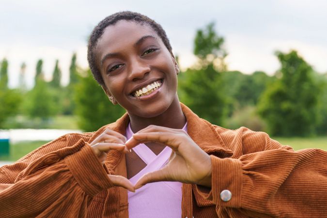 Portrait of a Black woman making an heart shape with hands