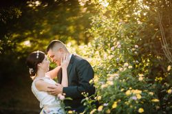Smiling groom and bride hugging and kissing in park