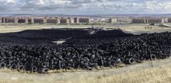 Heap of old tires between field near city