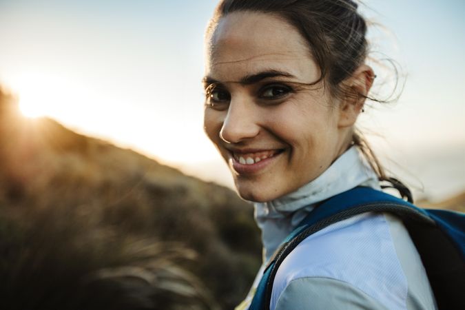 Adventurous female smiling over her shoulder before she starts her hike
