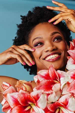 Studio shoot of smiling Black woman surrounded by flowers